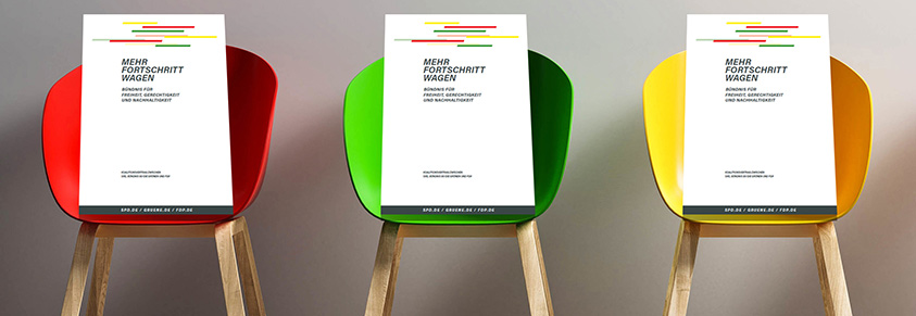 Drei Stühle in Ampelfarben, darauf jeweils das Deckblatt des Koaltionsvertrages