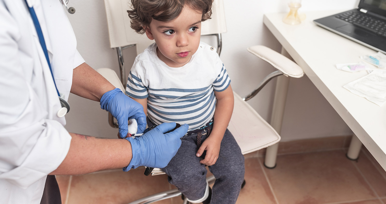 Kinderarzt nimmt kleinem Jungen Blut ab.