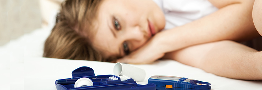 Eine Frau liegt traurig auf dem Bett und betrachtet ein Blutzuckermessgerät