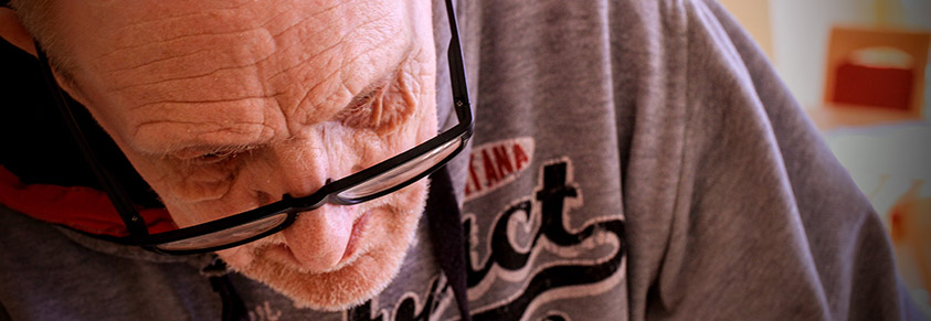 Ein älterer Mann sitzt schwach mit gesenktem Haupt lethargisch da