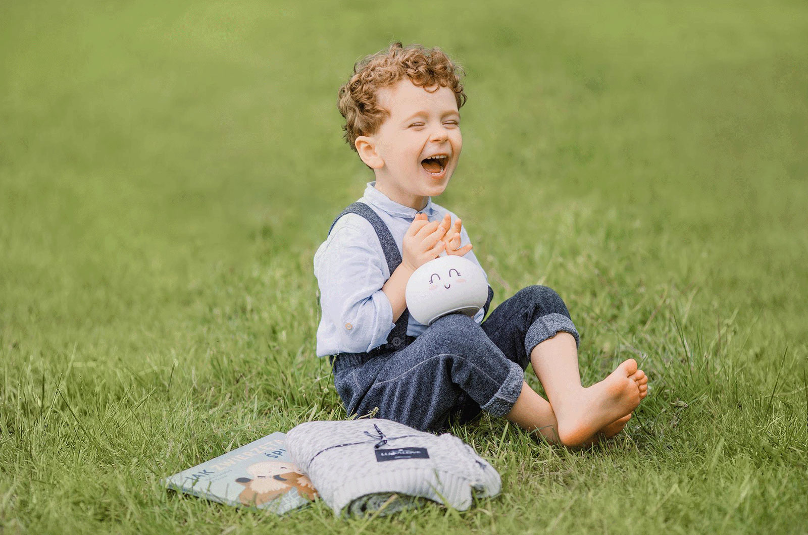 lachender kleiner Junge lachender kleiner Junge, barfuß auf der Wiese sitzend