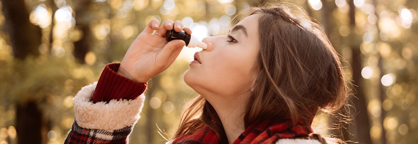 Frau im Wald nimmt ein Nasenspray