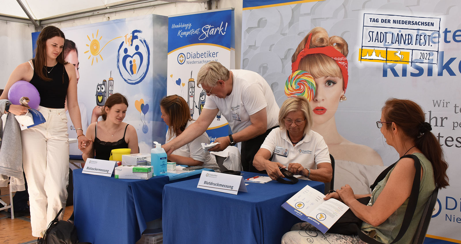 Risikotest vermehrt für junge Menschen interessant Eine Gruppe Menschen vom DNI führt den Diabetes-Risikotest mit zwei jungen Frauen durch