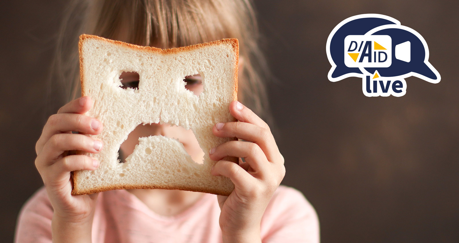 Ein trauriges Kind schaut durch eine Scheibe Weizen-Weißbrot, in die ein trauriges Gesicht geschnitten ist