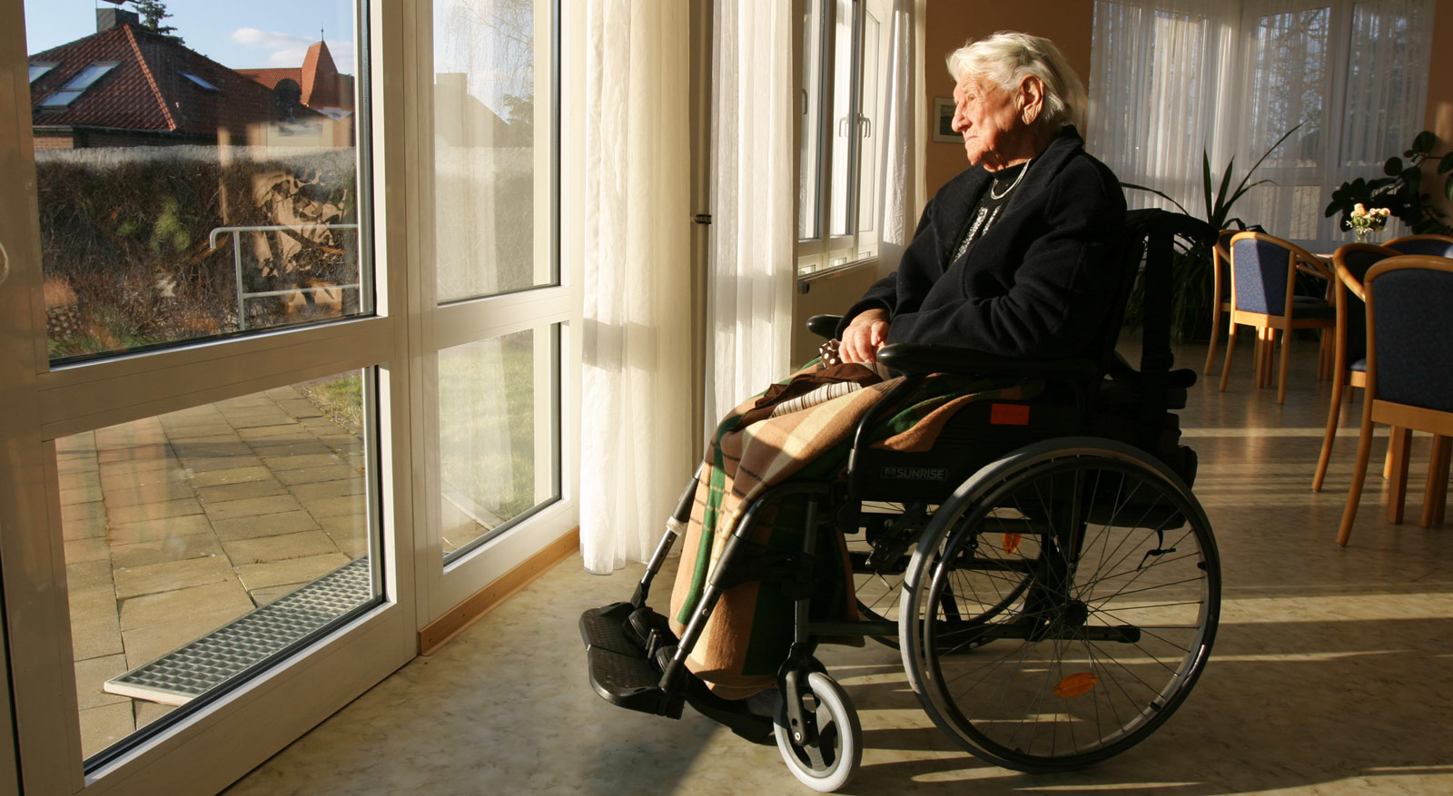 Eine ältere Dame einsam und traurig im Rollstuhl in einem Pflegeheim
