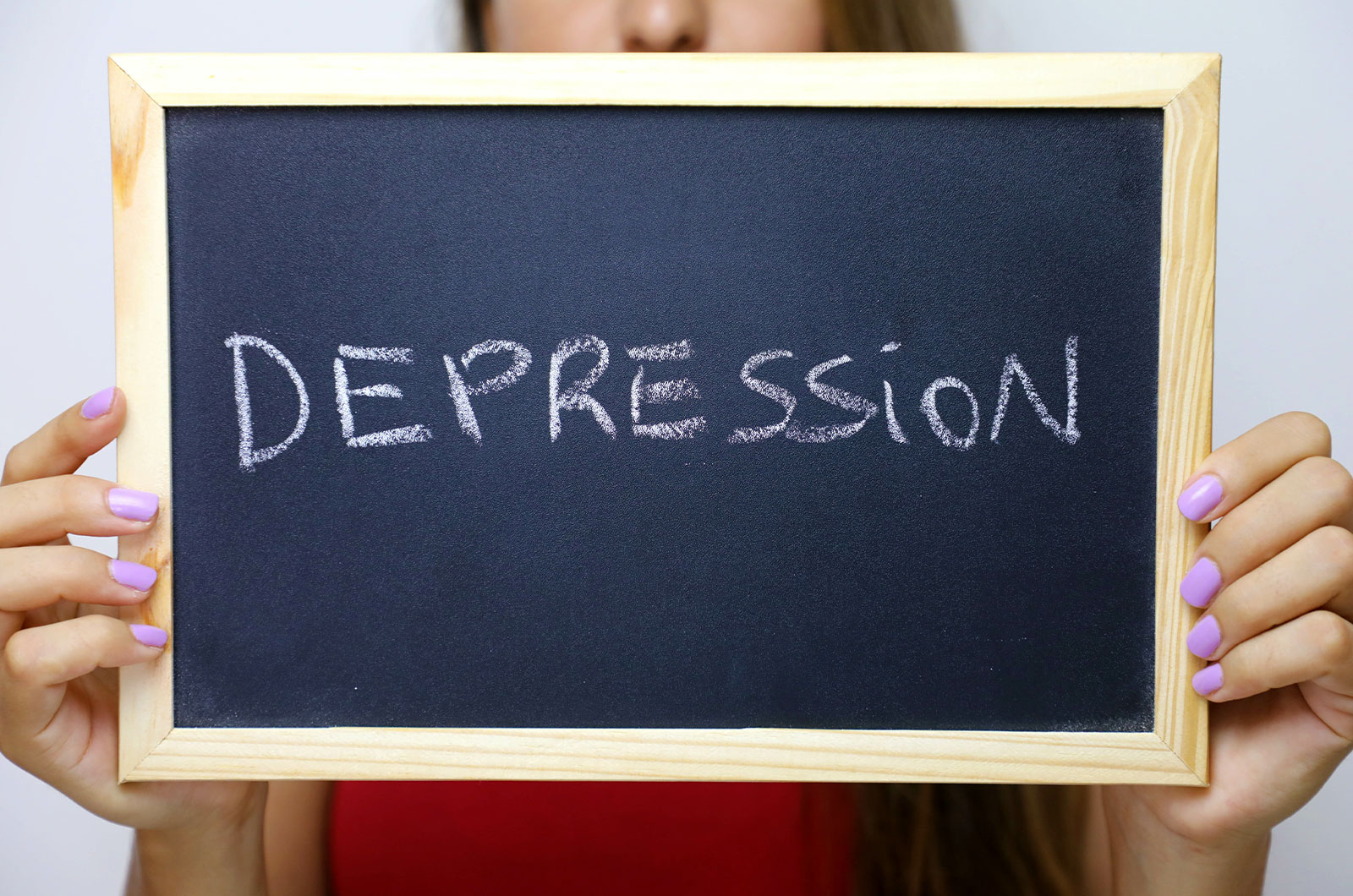 Depression auf eine Tafel geschrieben, die mit beiden Händen von einer jungen, nicht zu sehenden Frau gehalten wird