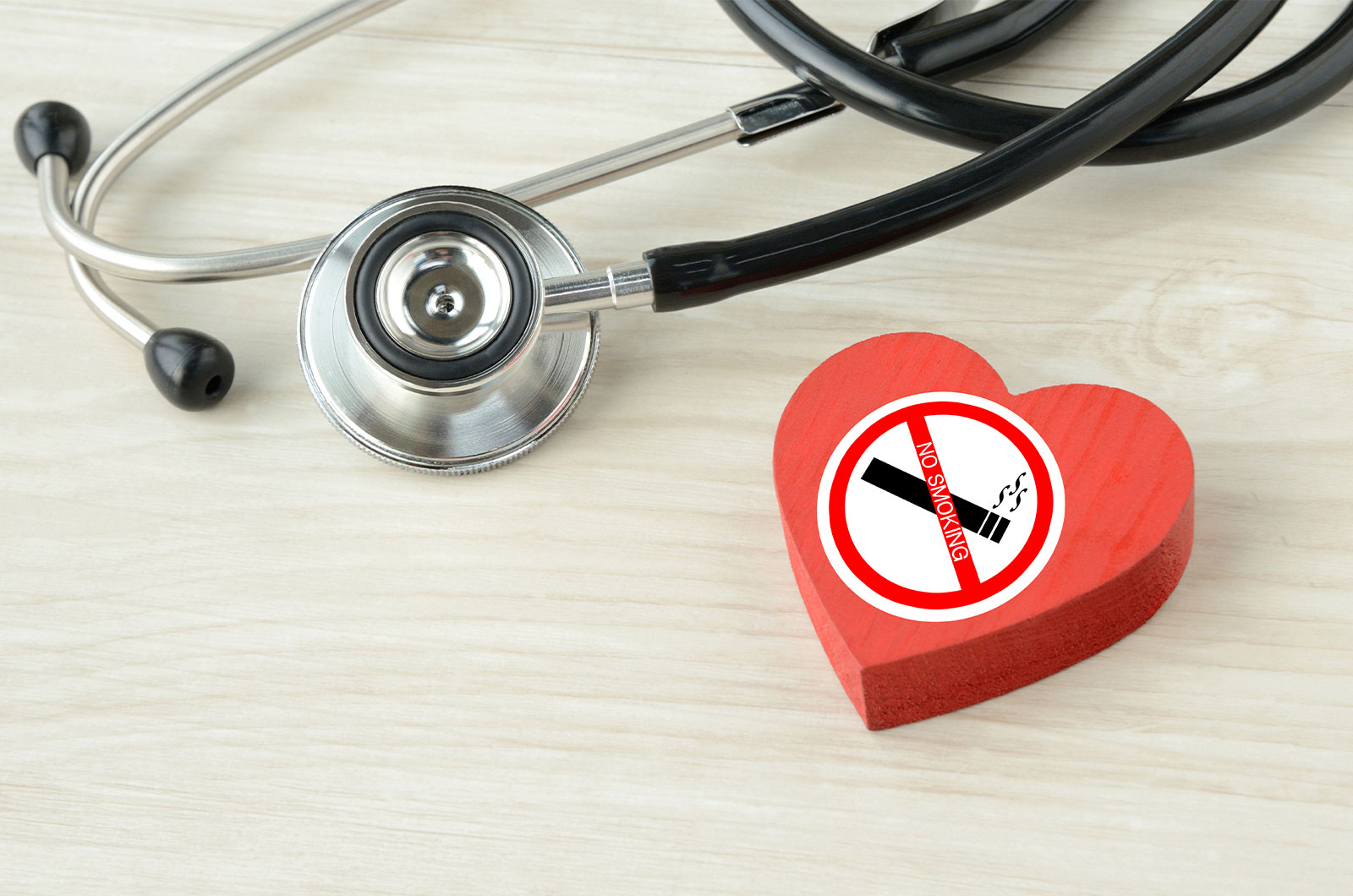 Herzobjekt mit Nichtraucheraufkleber und Stethoskop liegen auf einem Tisch