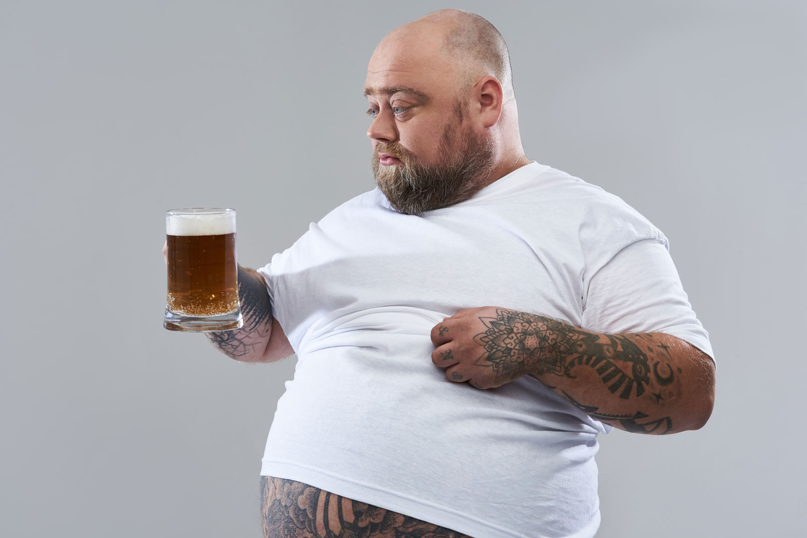 Ein korpulenter Mann schaut fragend ein Bier an