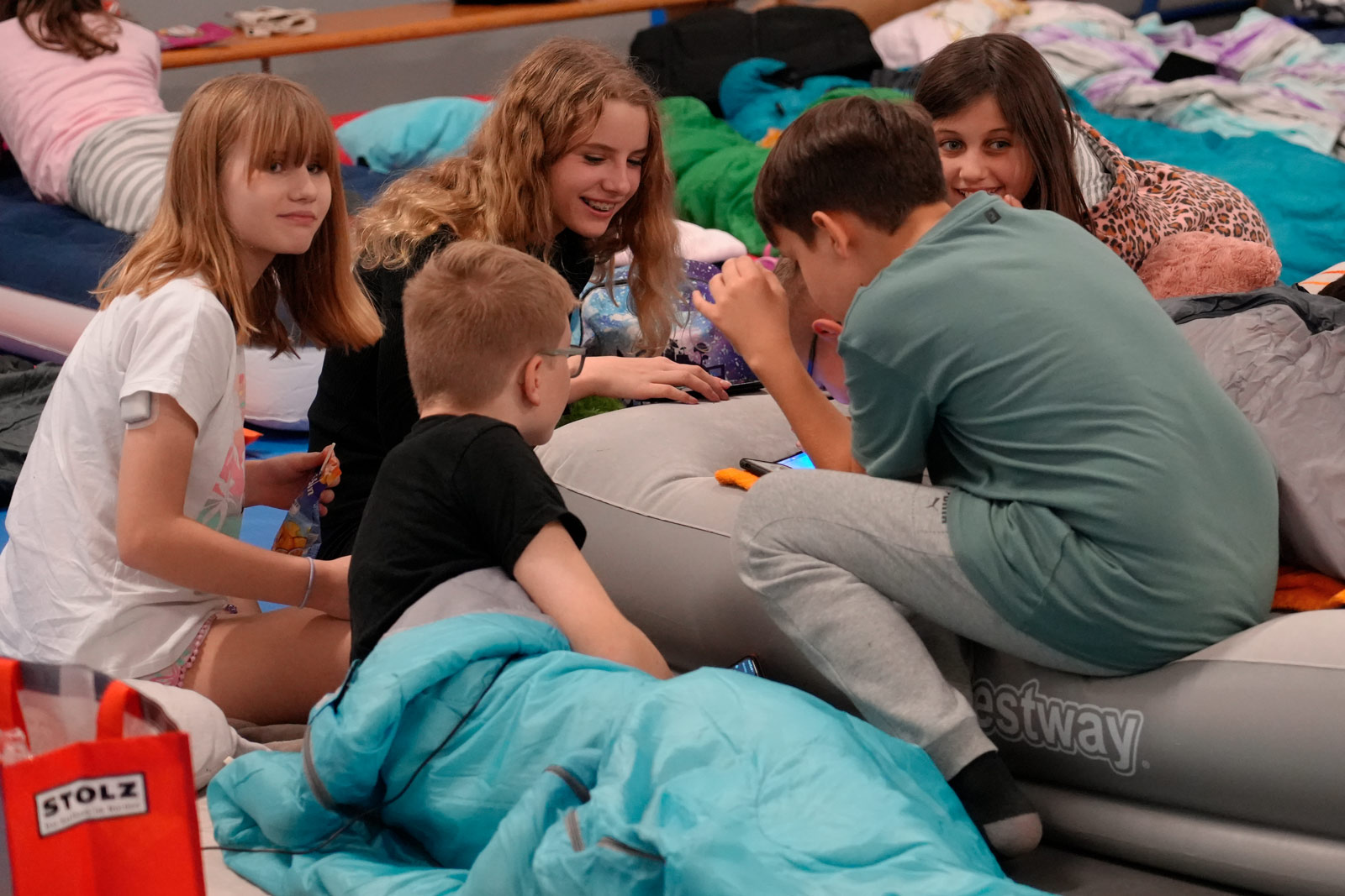 Eine Gruppe Kinder in Schlafklamotten sitzt beisammen und lacht