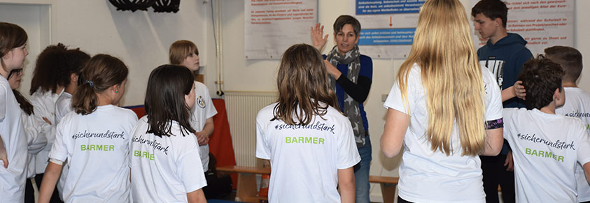 Claudia Brick-Deckert erjklärt einer Grupep Kinder etwas