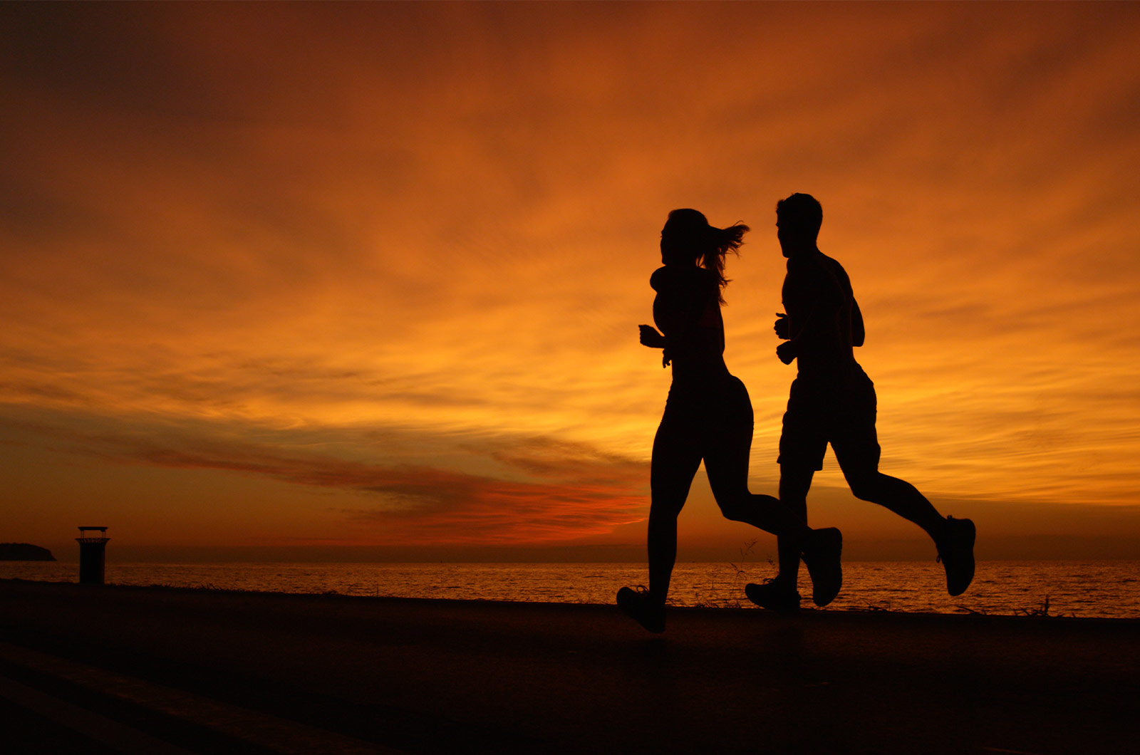 Mann und Frau beim Lauftraining, abends bei Sonnenuntergang