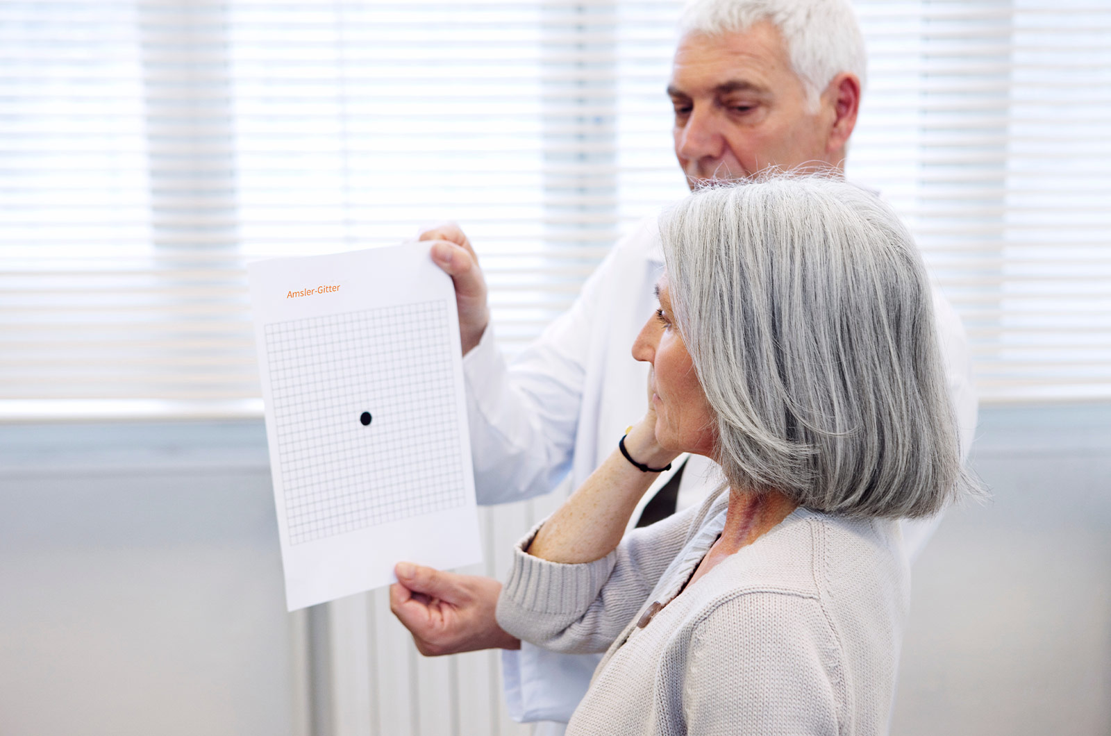 Frau beim Augenarzt, Überprüfung des Sehens mit einem Amsler-Test, Selbsttest bei altersabhängiger Makuladegeneration 
