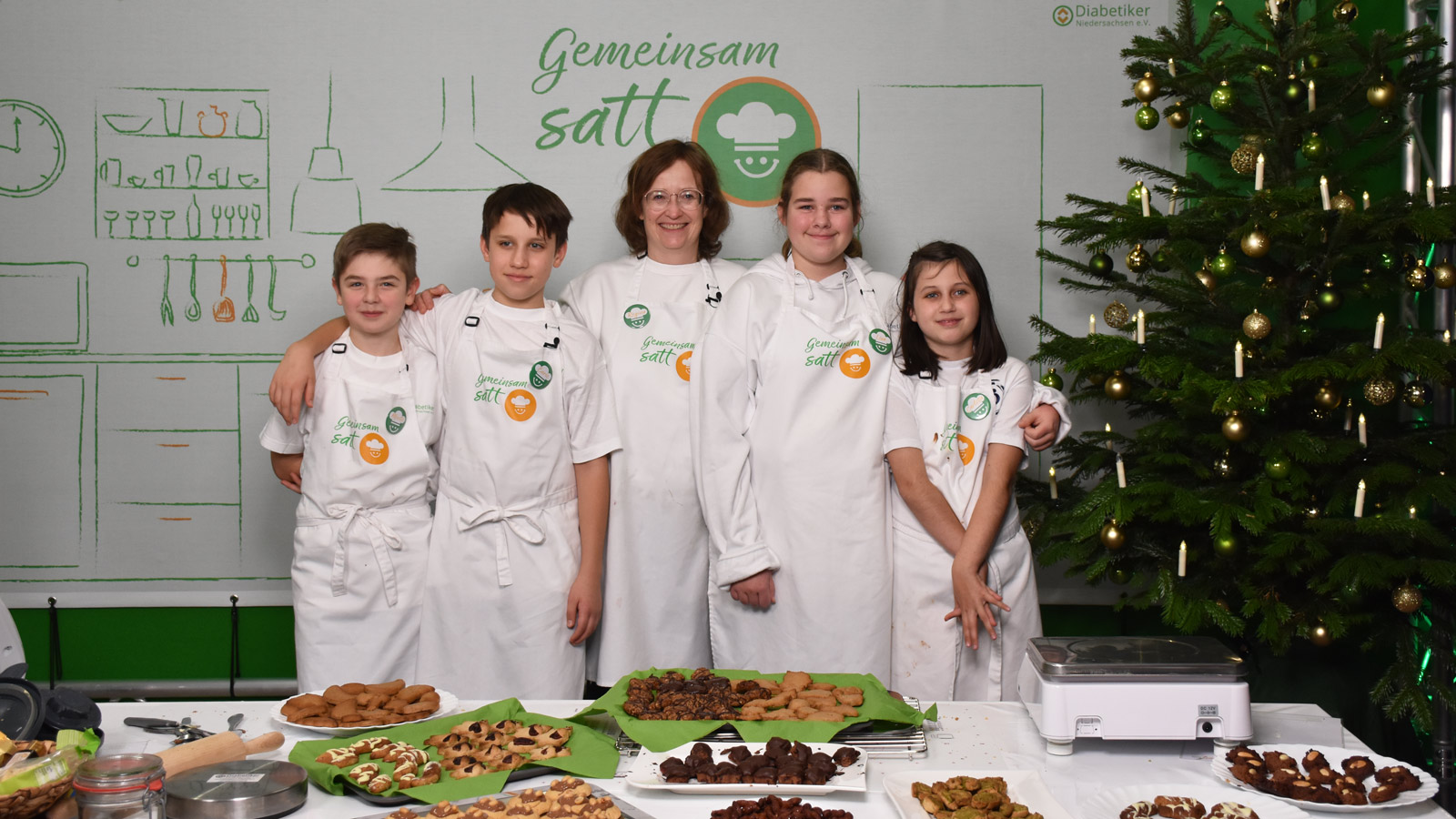 Die ganze Gruppe (4 Kinder + Regina Kröger) steht stolz vor verschiedenen Tellern mit Keksen