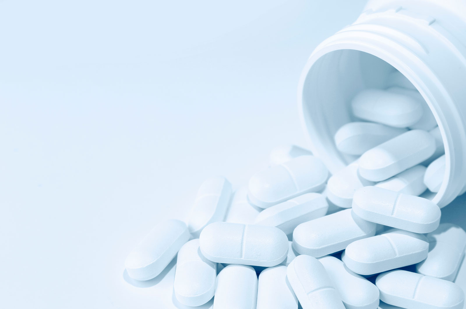 Medikament, einzelne Tabletten mit einem weißen Kunststoffbehälter