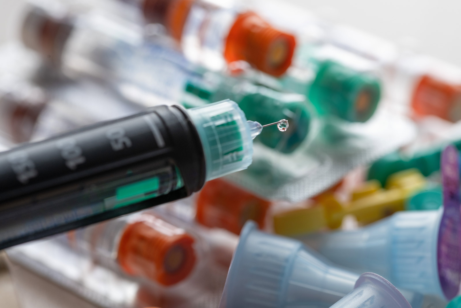 Eine Insulinspritze vor diversen Ampullen mit verschiedenfarbigen Ampullen