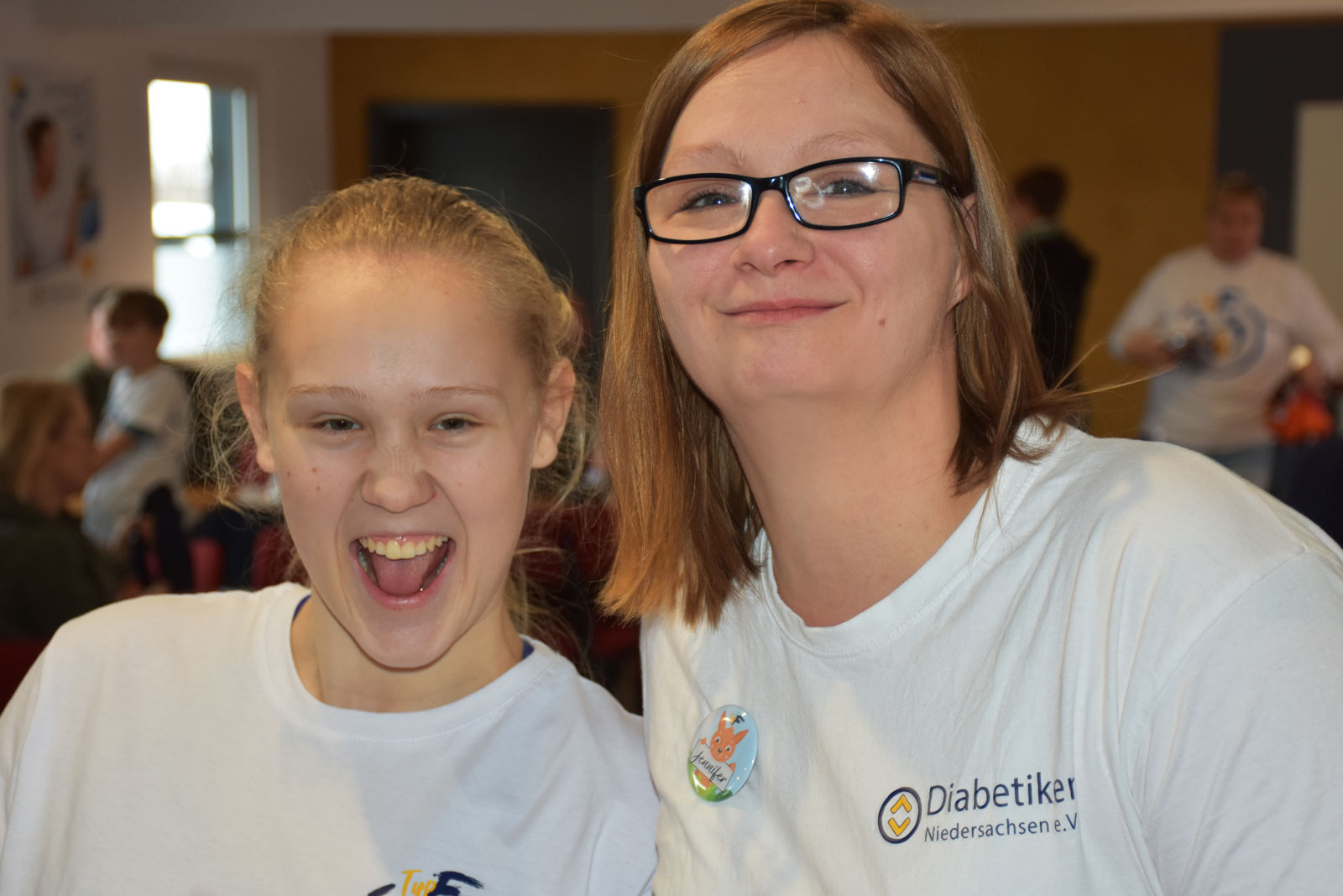 Zwei junge Frauen in Diabetiker Niedersachsen T-Shirts lachen in die Kamera