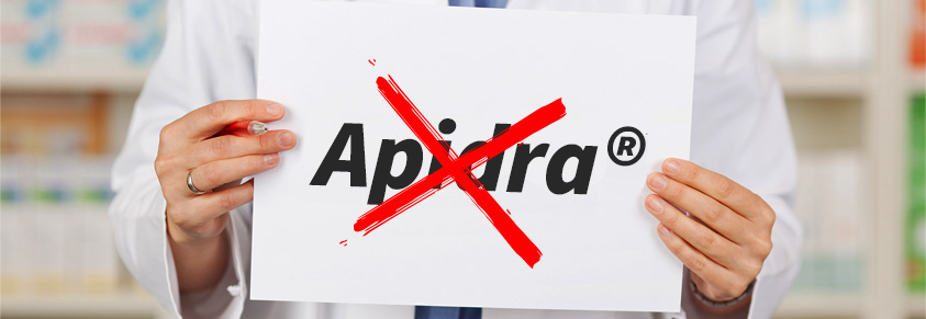 Eine Apothekerin hält ein Schild hoch. Darauf ist das Wort "Apidra" durchgestrichen