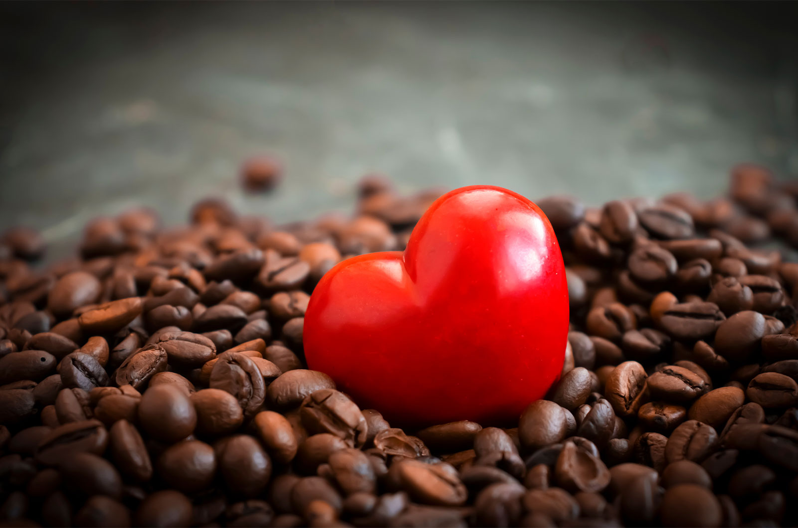 Kaffeebohnen, darin eingelegt ein rotes Herz