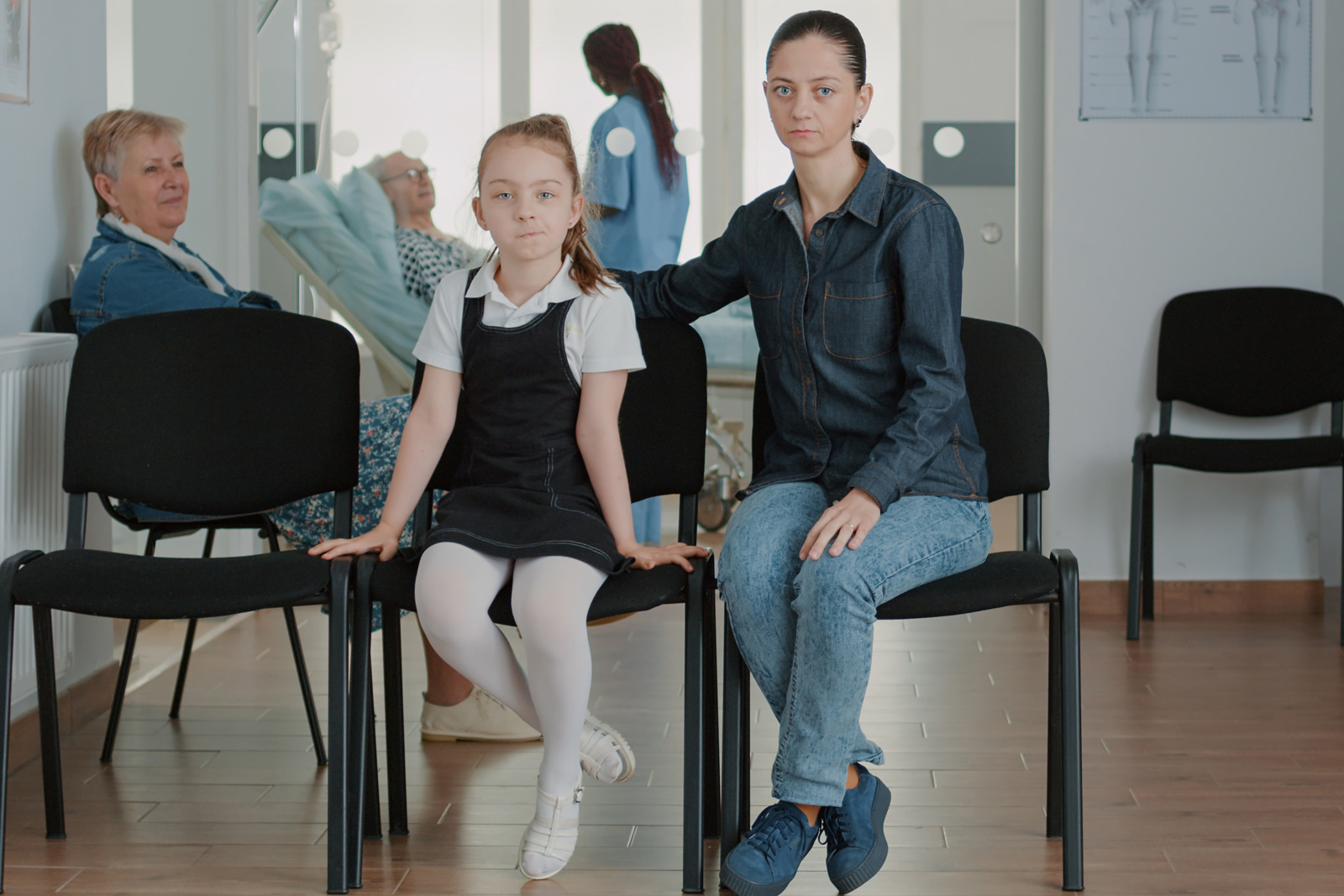 Eine Mutter und ihre Tochter sitzen mit betroffenem Gesicht in einem Wartezimmer