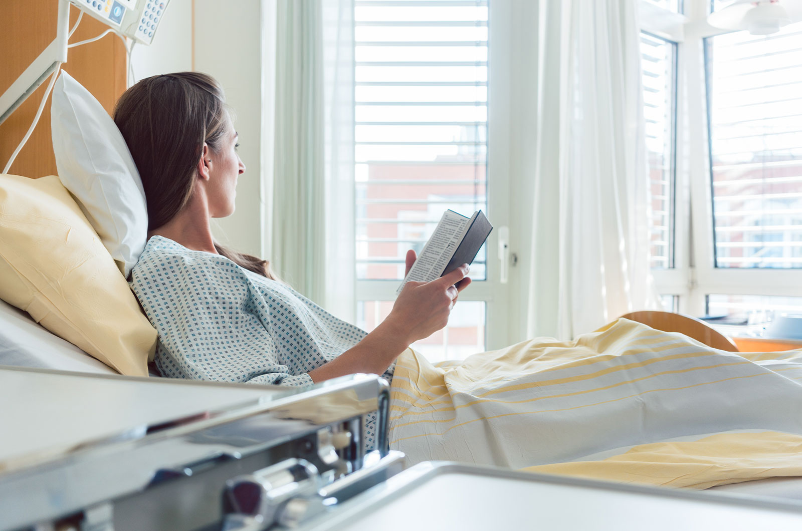 nach der OP junge Frau mi Diabetes nach einer OP im Krankenbett mit einem Buch