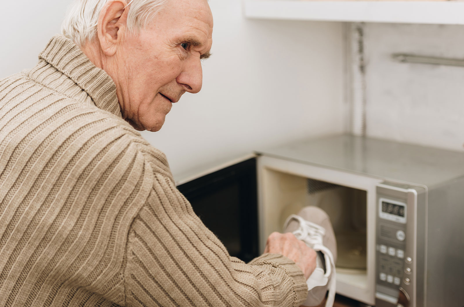 älterer Mann mit Demenzerkrankung steckt Schuh in Mikrowelle
