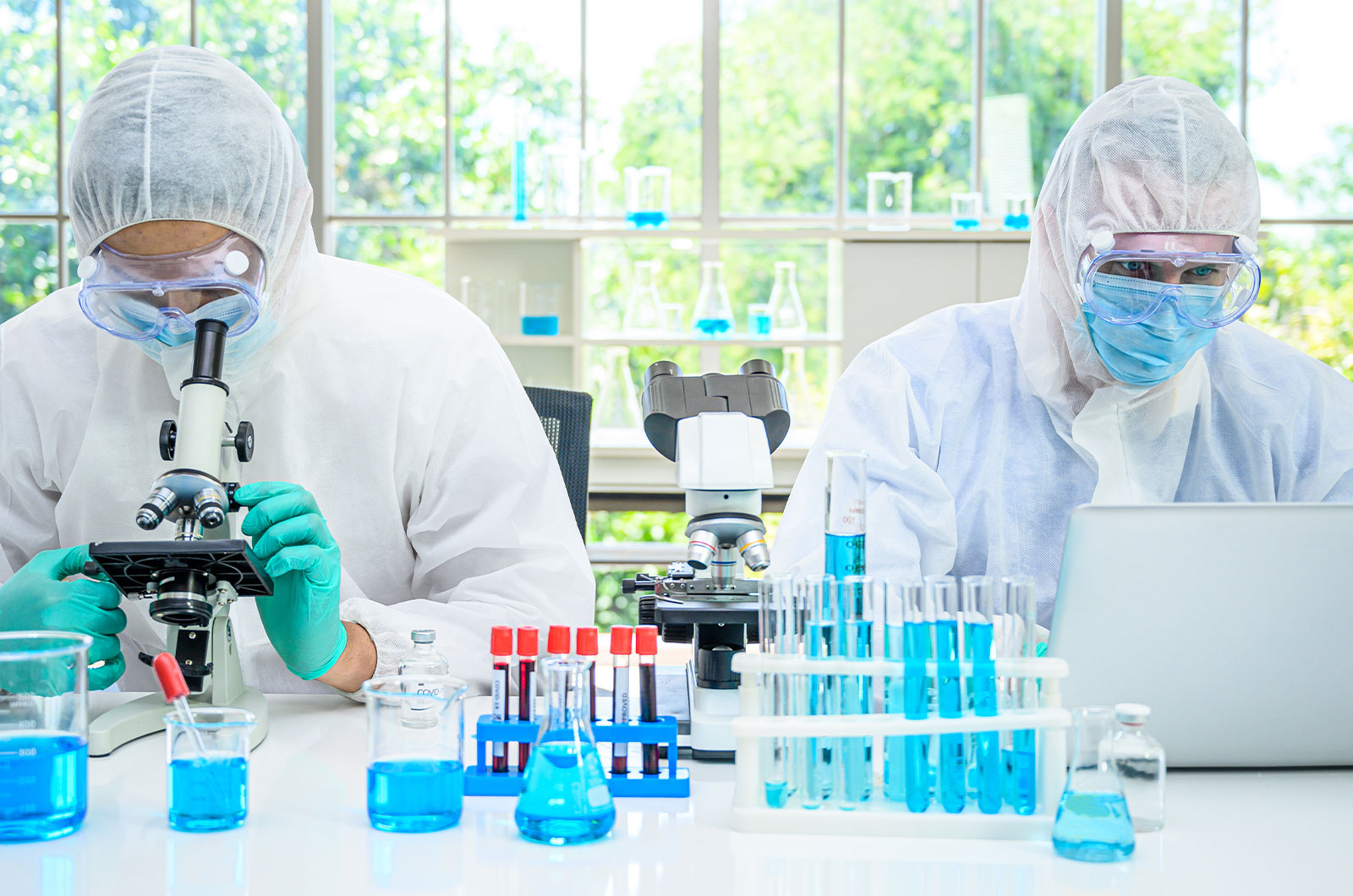 Laboranten im Schutzanzug prüfen und testen sorgsam im Labor Substanzen