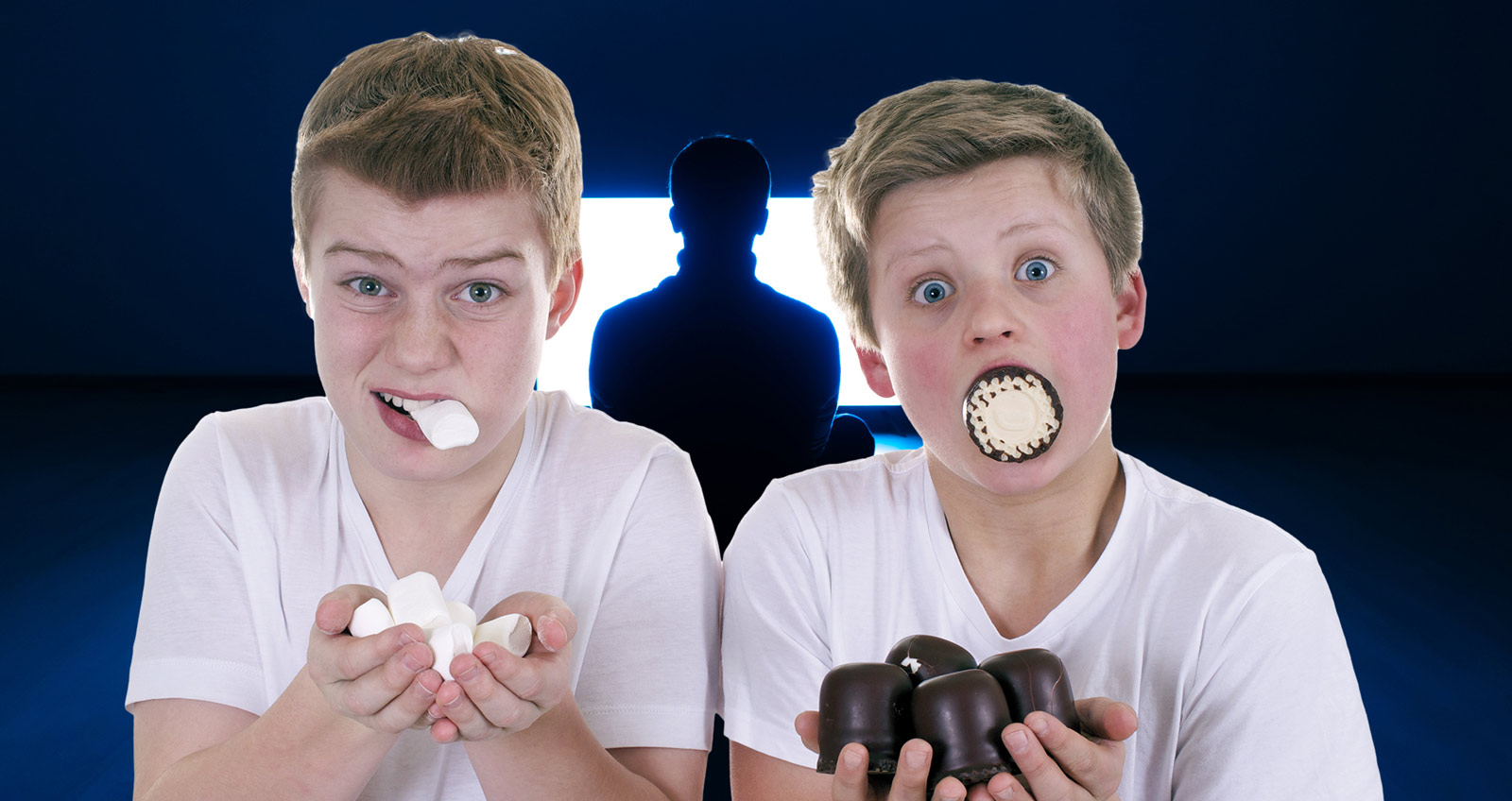Zwei Jungs stopfen sich mit Süßigkeiten voll, dahinter ein flimmernder Fernseher