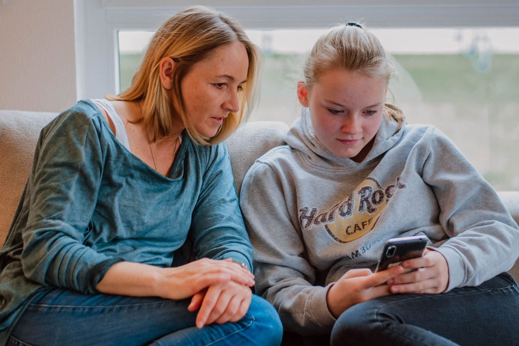 Katja Schaaf betrachtet zusammen mit einerm jungen Mädchen Sensorwerte auf einem Handy