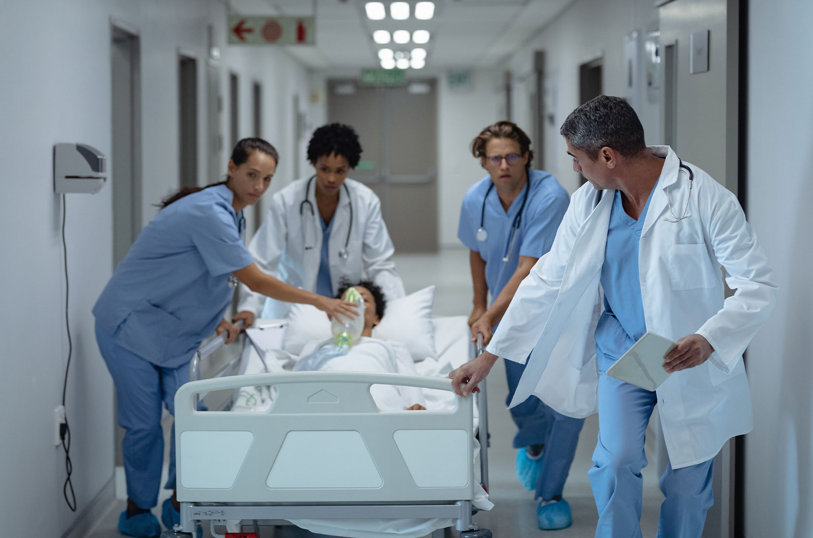 ein medizinisches Team schiebt Patientin auf einem Notfallbett zur Behandlung