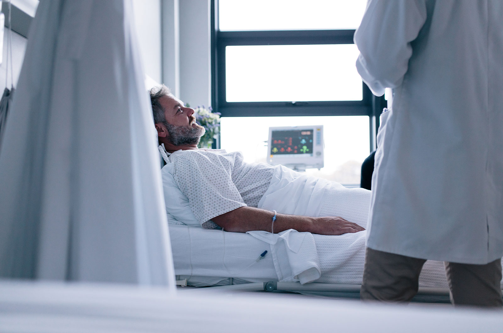 Mann mit psychischer Erkrankung im Krankenhausbett, behandelnder Arzt bei Visite