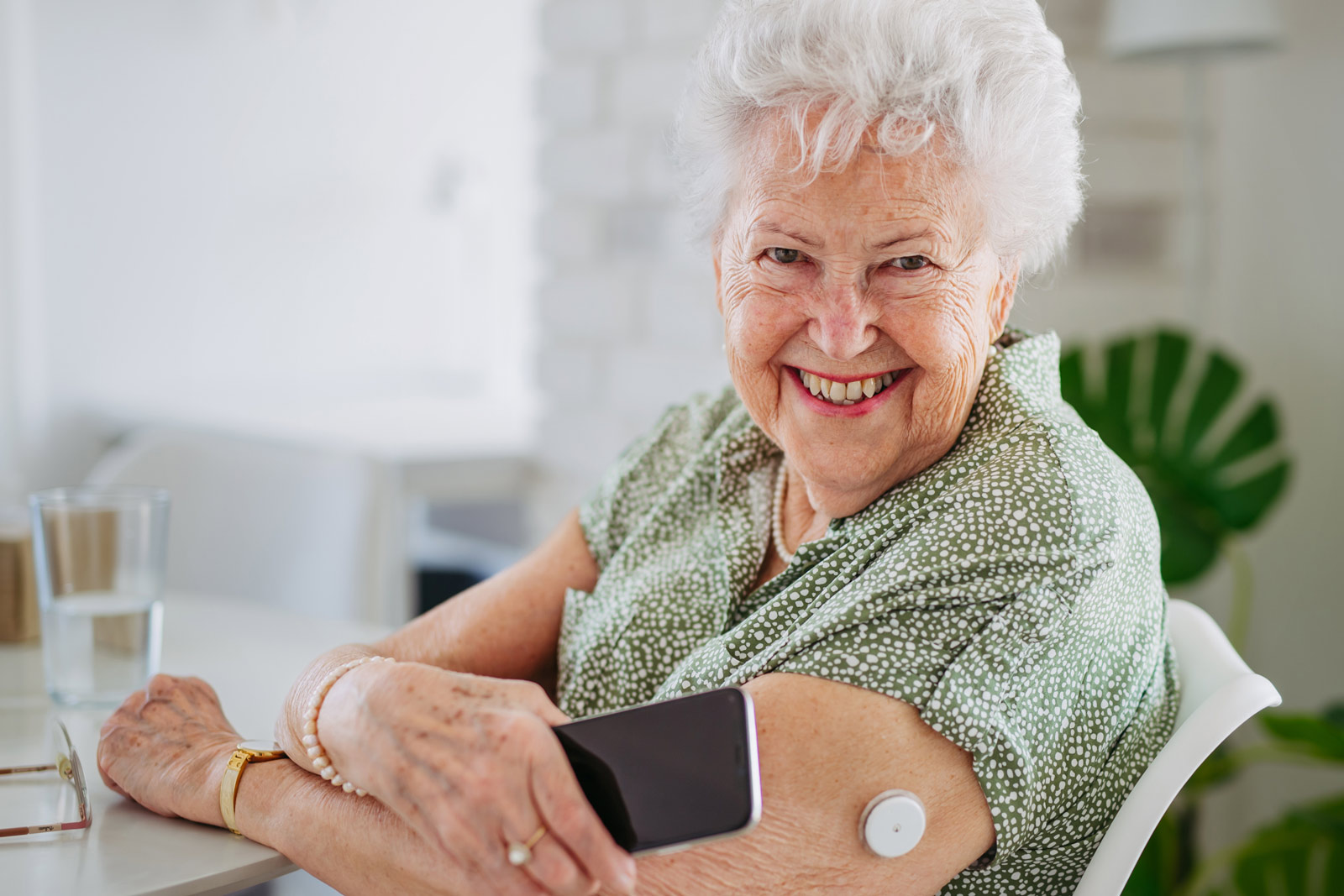 Eine ältere Dame misst mit einem CGM-Gerät ihren Zucker