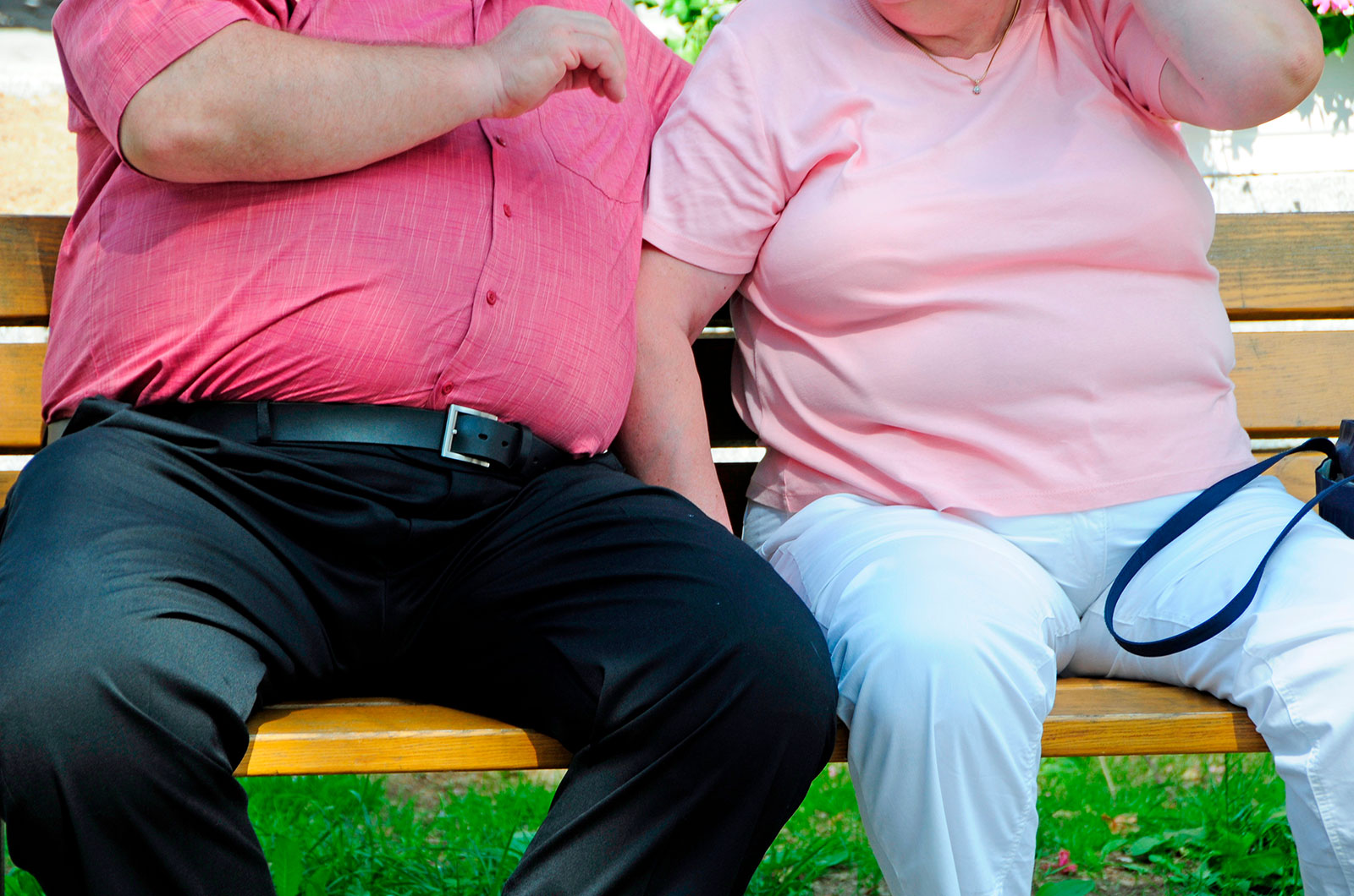 Risikofaktor Übergewicht, älteres Paar sitzend auf einer Bank 