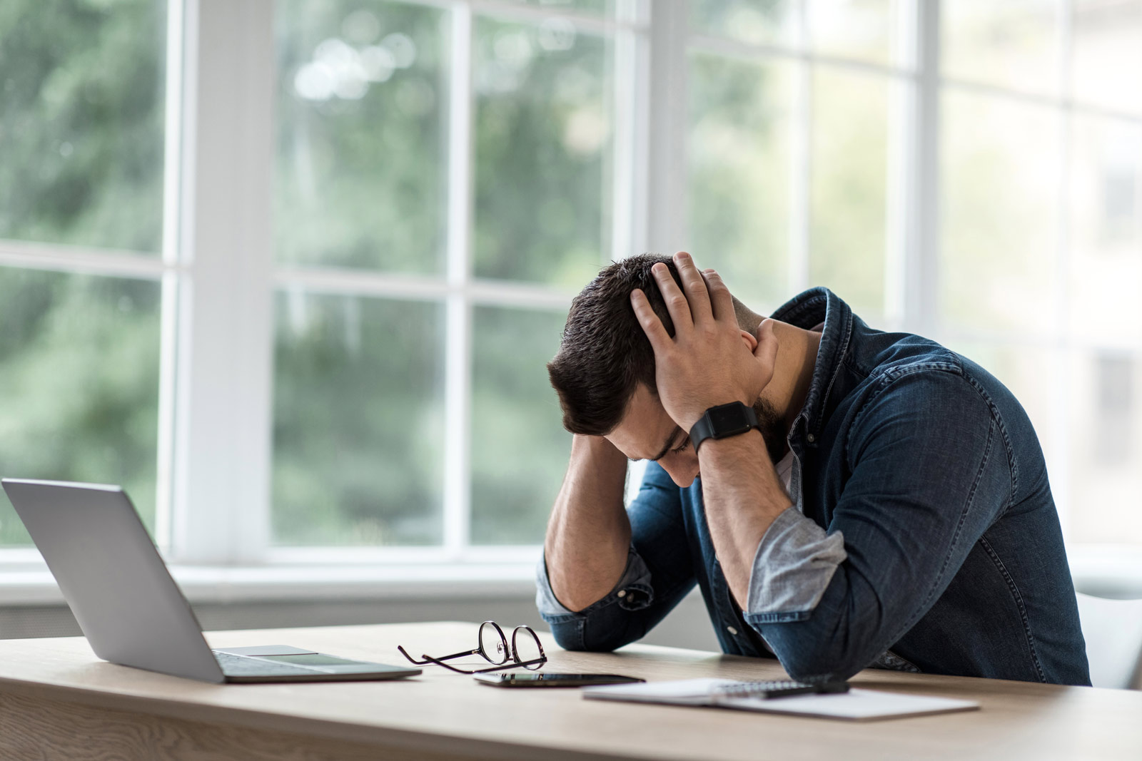 Stress bei der Arbeit Ein Mann sitzt gestresst vor einem Laptop