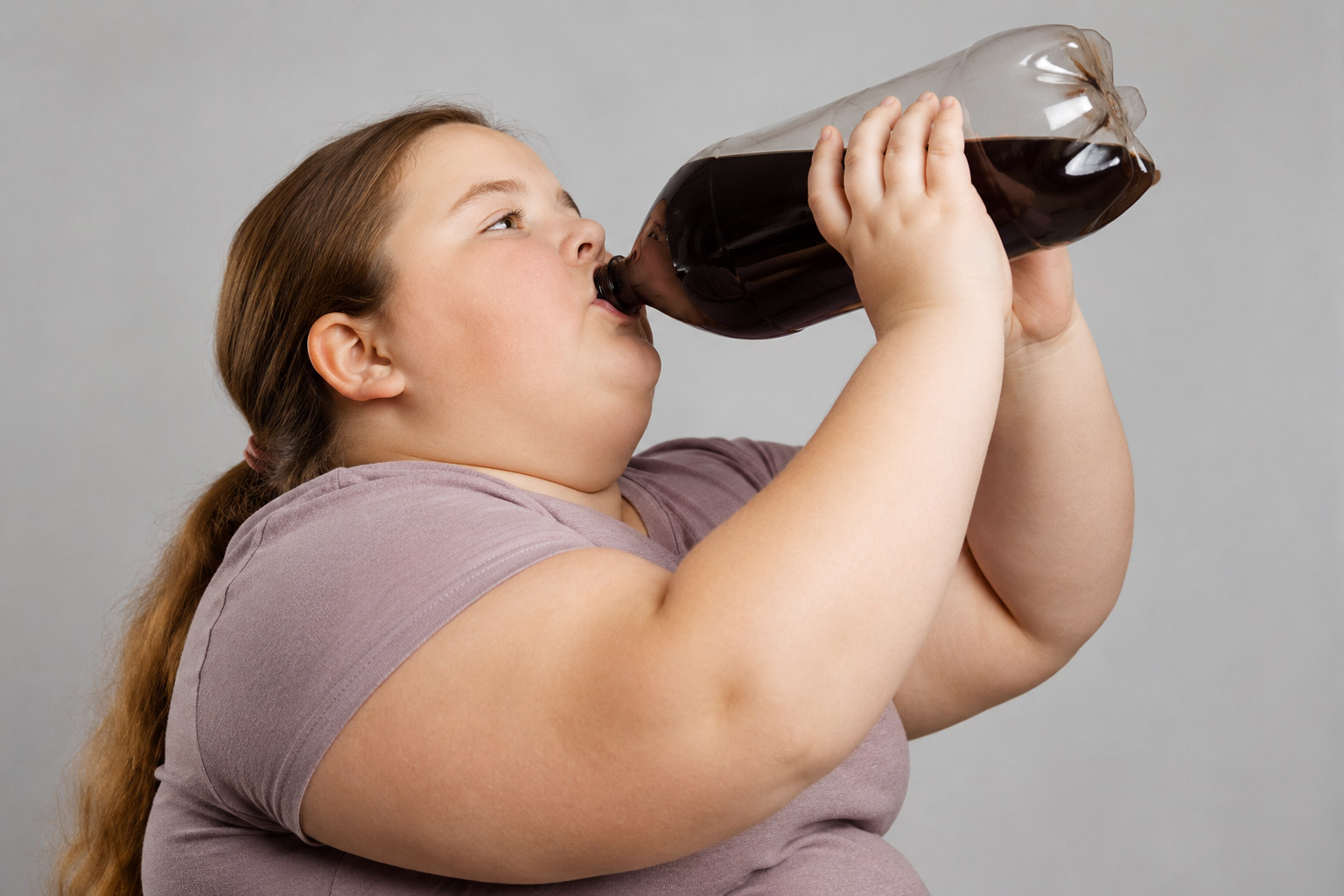Ein übergewichtiges Mädchen trinkt Cola
