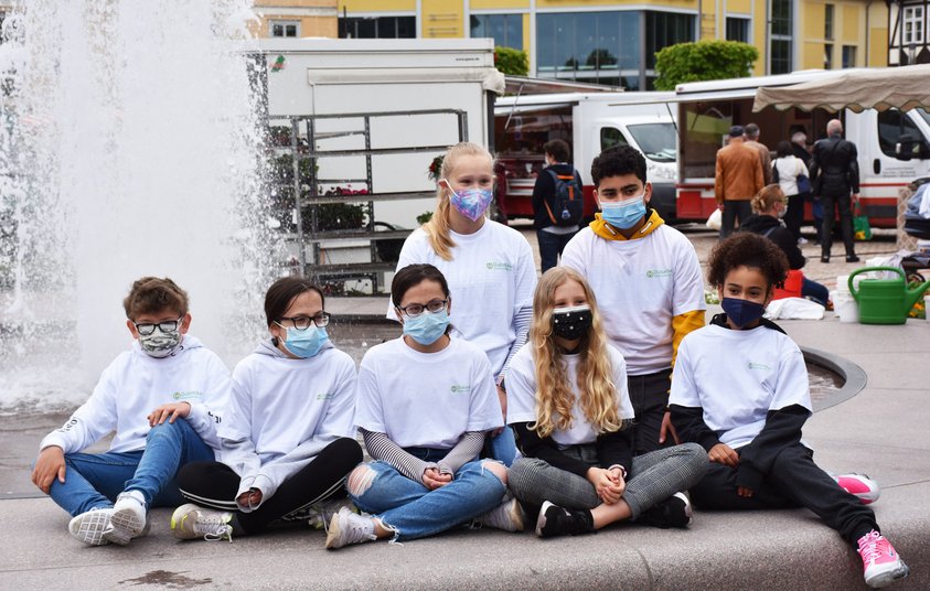 Gemeinsam satt Typ F-Kinder mit Maske am Brunnen