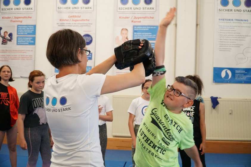 Sicher & Stark Ein Kind übt Selbstverteidigung mit einer Trainerin